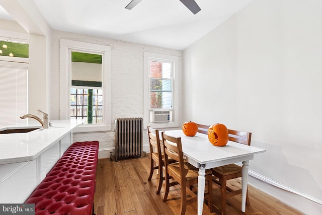 dining space featuring ceiling fan, sink, hardwood / wood-style floors, radiator heating unit, and lofted ceiling