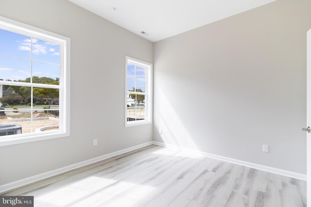 empty room with light hardwood / wood-style flooring and plenty of natural light