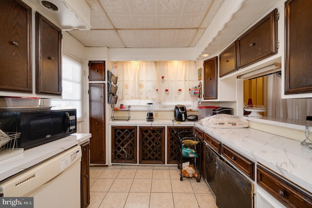 kitchen featuring dishwasher, dark brown cabinets, and light tile patterned floors