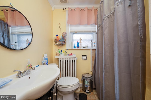 bathroom featuring toilet, crown molding, radiator heating unit, and sink