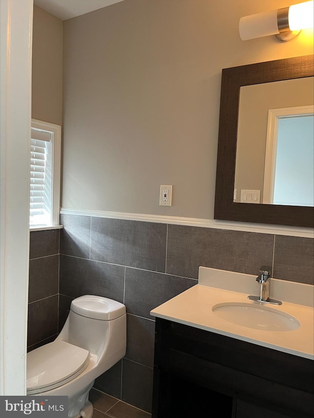 bathroom featuring tile patterned flooring, vanity, toilet, and tile walls