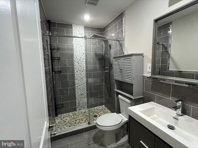 bathroom featuring backsplash, vanity, a shower with door, tile walls, and toilet