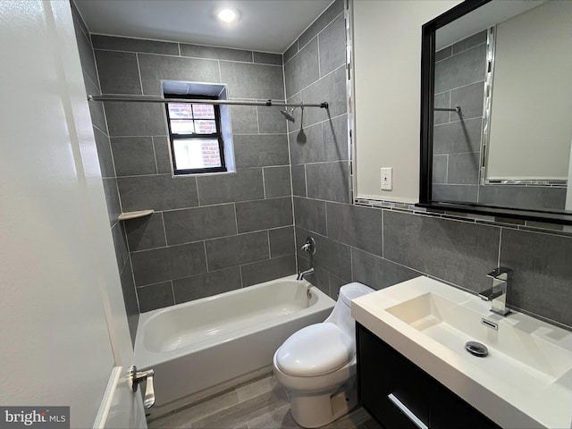 full bathroom featuring vanity, backsplash, tiled shower / bath, toilet, and tile walls