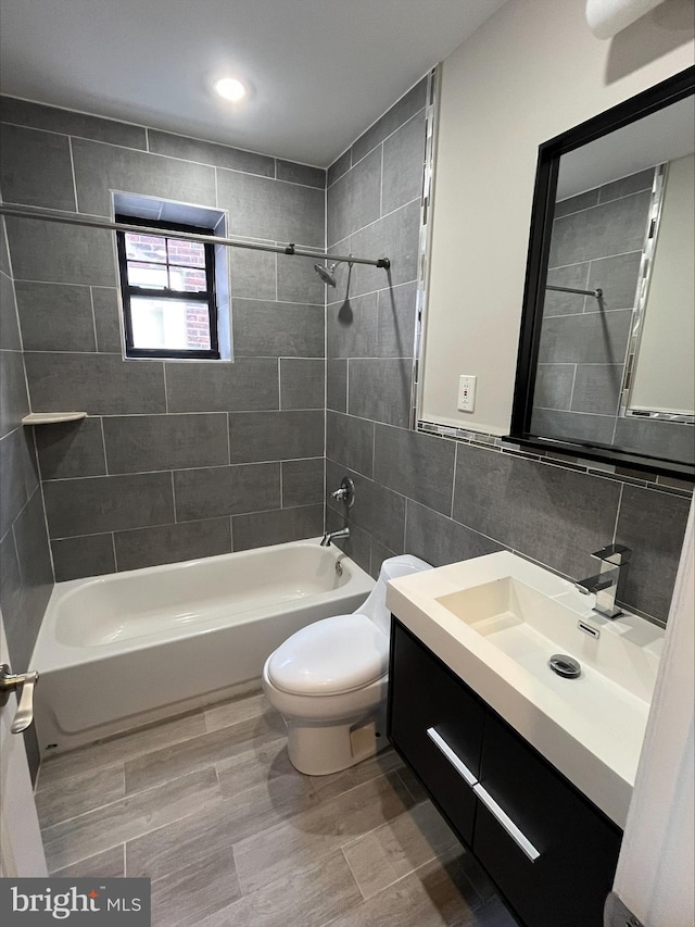 full bathroom featuring tasteful backsplash, toilet, vanity, tile walls, and tiled shower / bath