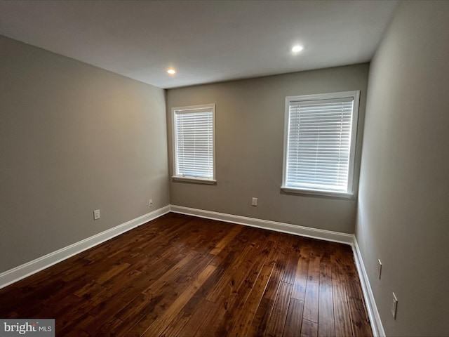 empty room with dark hardwood / wood-style flooring and a wealth of natural light