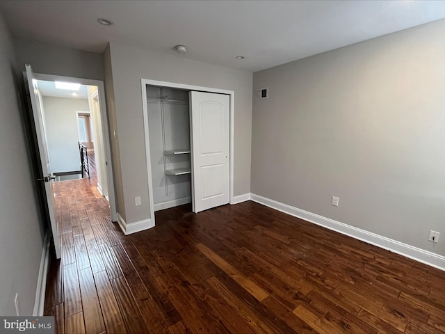 unfurnished bedroom featuring dark hardwood / wood-style flooring and a closet