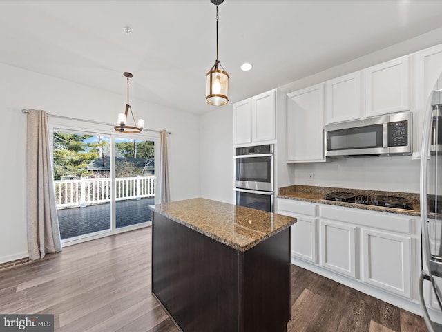 kitchen with dark stone countertops, stainless steel appliances, a center island, and white cabinets