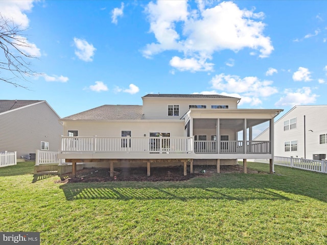 back of property featuring a lawn, a sunroom, and a deck