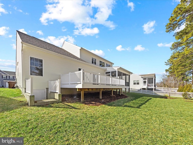 back of house featuring a sunroom, a deck, and a lawn