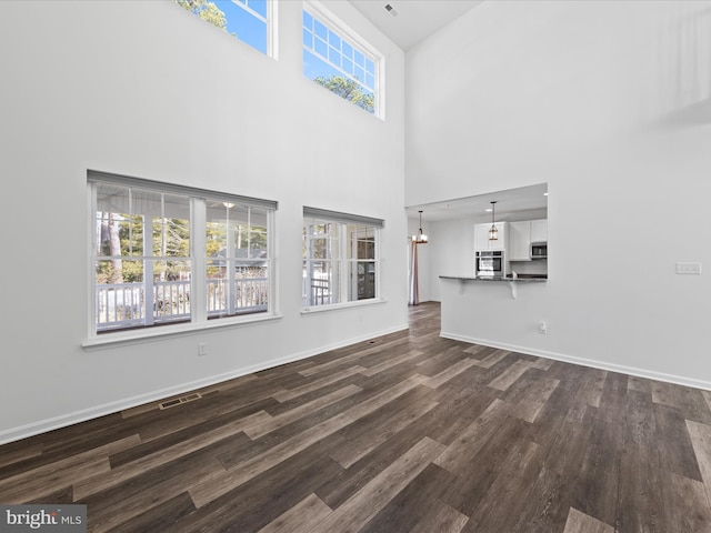 unfurnished living room with a towering ceiling and dark hardwood / wood-style flooring