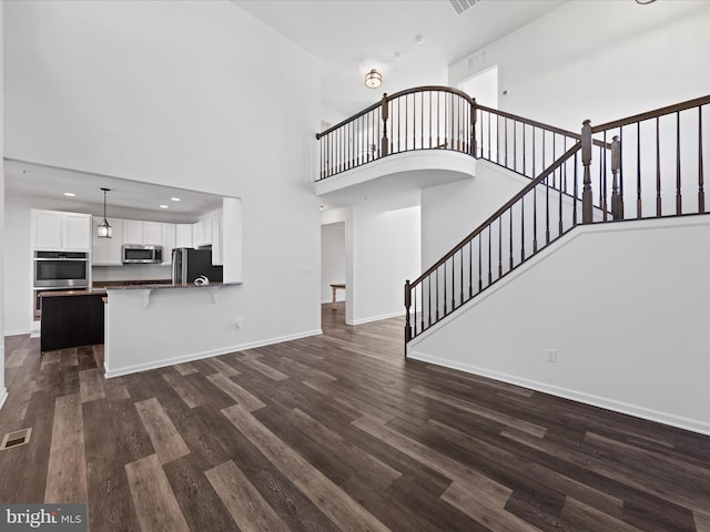 unfurnished living room featuring dark hardwood / wood-style floors and a high ceiling