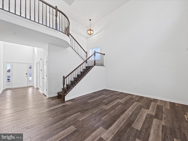 foyer featuring dark hardwood / wood-style flooring, an inviting chandelier, and a high ceiling