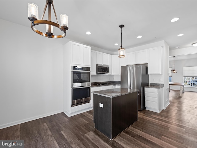 kitchen with decorative light fixtures, stainless steel appliances, dark stone counters, and a kitchen island