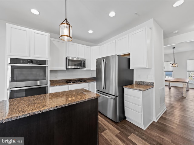 kitchen with stainless steel appliances, white cabinetry, and decorative light fixtures