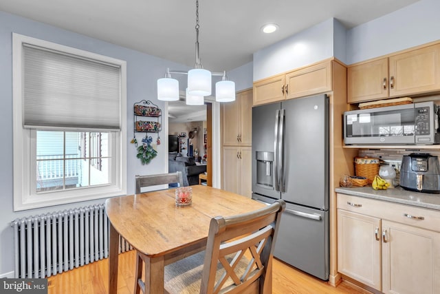 kitchen featuring decorative light fixtures, a notable chandelier, appliances with stainless steel finishes, light brown cabinets, and radiator heating unit