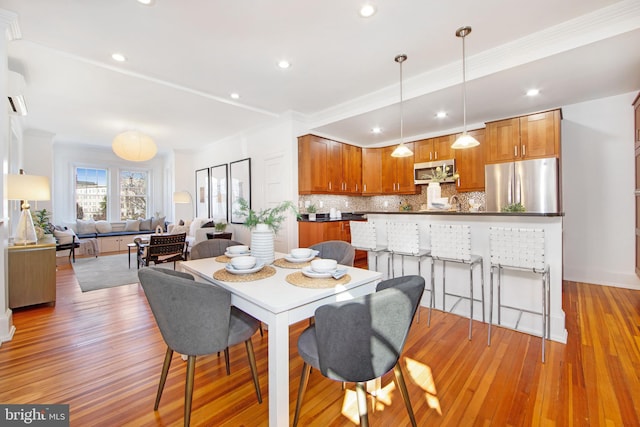 dining area with recessed lighting, ornamental molding, and light wood finished floors