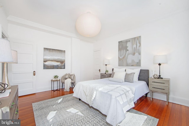 bedroom with crown molding, baseboards, and wood finished floors