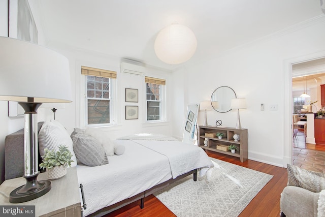 bedroom featuring crown molding, wood finished floors, baseboards, and a wall mounted air conditioner