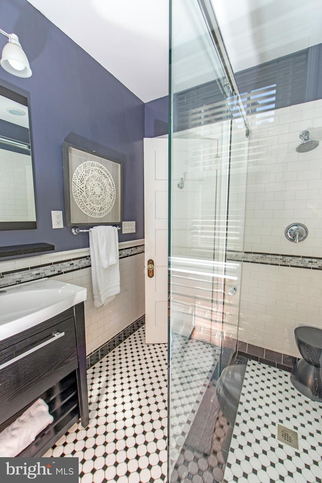 full bath featuring a shower stall, tile walls, a wainscoted wall, tile patterned floors, and vanity