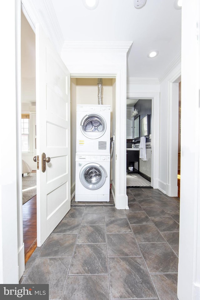 washroom featuring stacked washer and dryer, crown molding, and laundry area