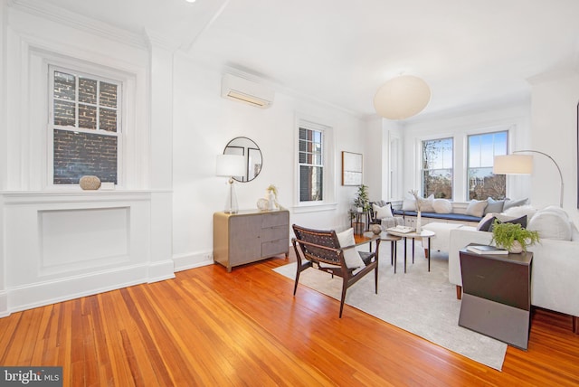 living room featuring a wall unit AC, light wood finished floors, and ornamental molding