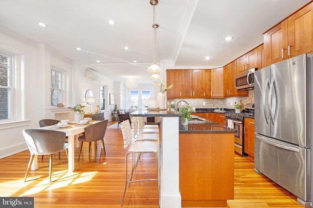 kitchen featuring dark countertops, backsplash, a kitchen bar, appliances with stainless steel finishes, and a sink