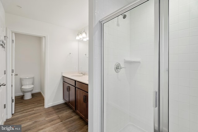 bathroom with hardwood / wood-style flooring, a shower with door, vanity, and toilet