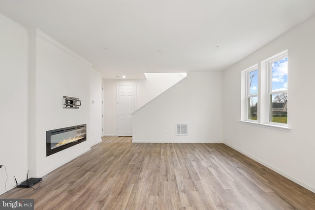 unfurnished living room featuring light hardwood / wood-style flooring and ornamental molding