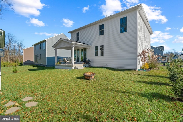 back of property with a yard and an outdoor fire pit