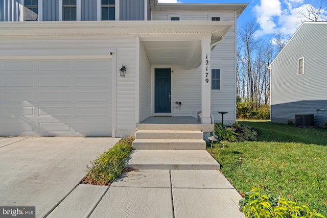 view of exterior entry featuring a garage, a yard, and central AC