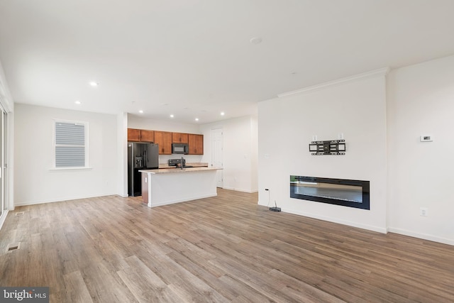 unfurnished living room featuring crown molding and light wood-type flooring