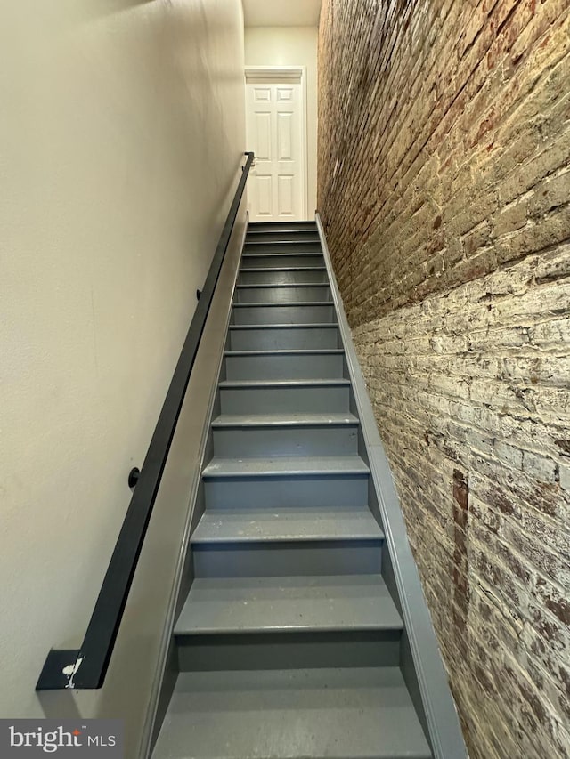 stairway featuring brick wall