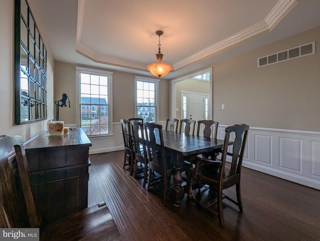 dining room with dark hardwood / wood-style flooring, crown molding, and a tray ceiling