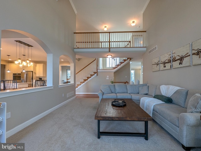 living room with ornamental molding, a towering ceiling, and carpet flooring