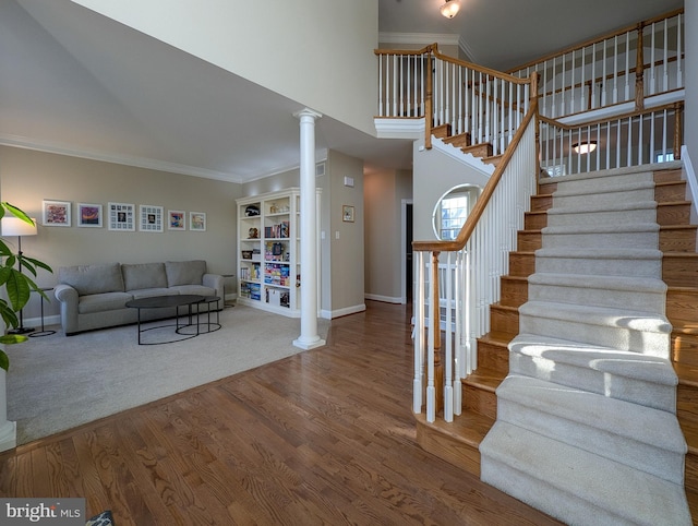 stairs featuring decorative columns, crown molding, and hardwood / wood-style flooring