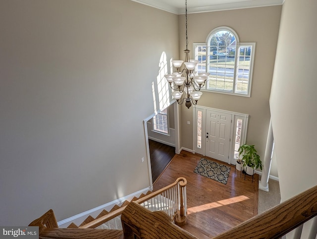 entrance foyer with dark wood-type flooring, an inviting chandelier, and ornamental molding