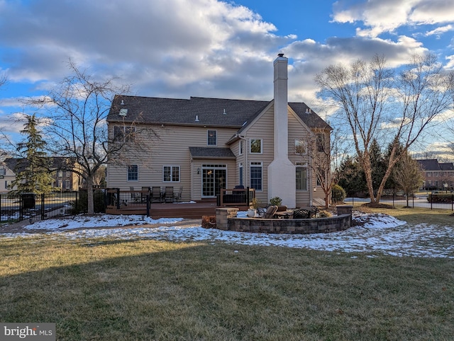 snow covered rear of property with a yard and a wooden deck