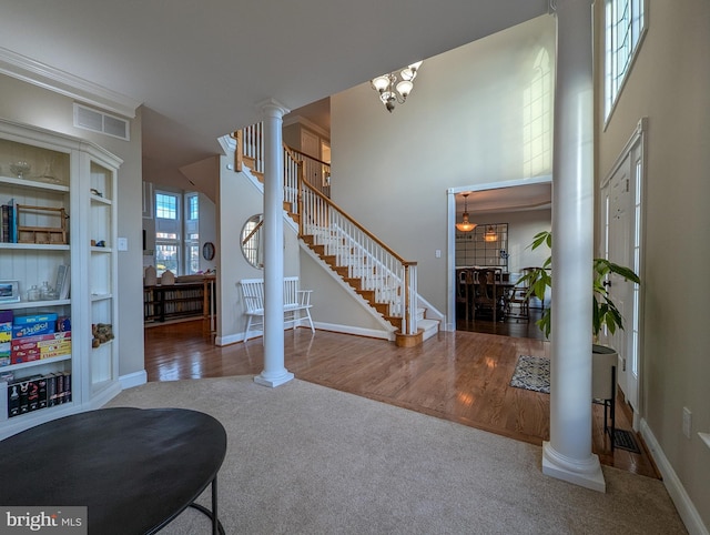 carpeted entryway featuring a chandelier and ornate columns