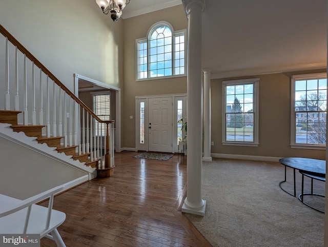 entryway with ornate columns, a towering ceiling, ornamental molding, and plenty of natural light