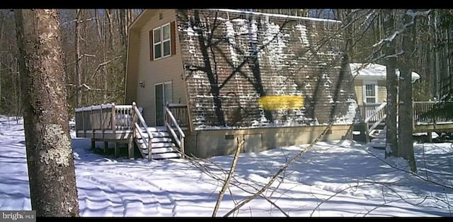 snow covered back of property featuring a deck