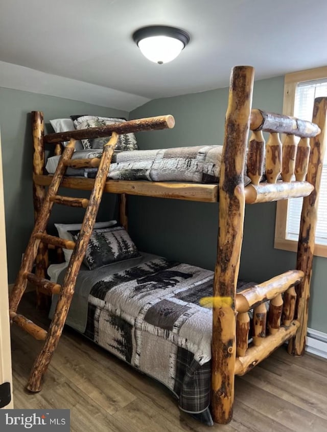 bedroom with multiple windows, hardwood / wood-style floors, and vaulted ceiling