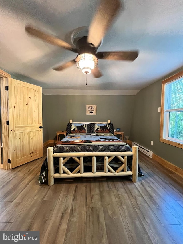 bedroom with a textured ceiling, ceiling fan, hardwood / wood-style flooring, and a baseboard heating unit