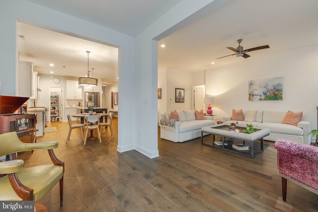 living room featuring ceiling fan and dark wood-type flooring