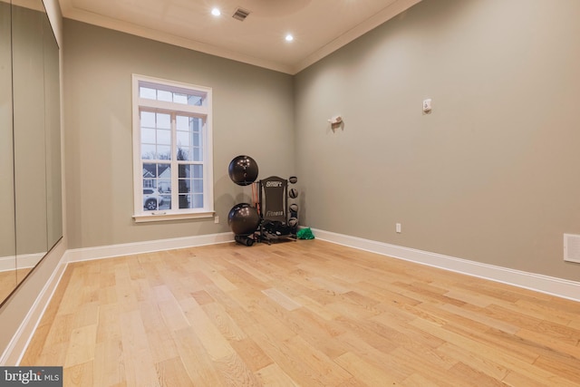 exercise area with crown molding and light hardwood / wood-style flooring