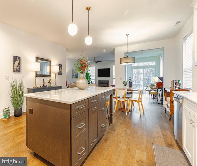 kitchen featuring stainless steel dishwasher, light hardwood / wood-style flooring, hanging light fixtures, a kitchen island, and ceiling fan