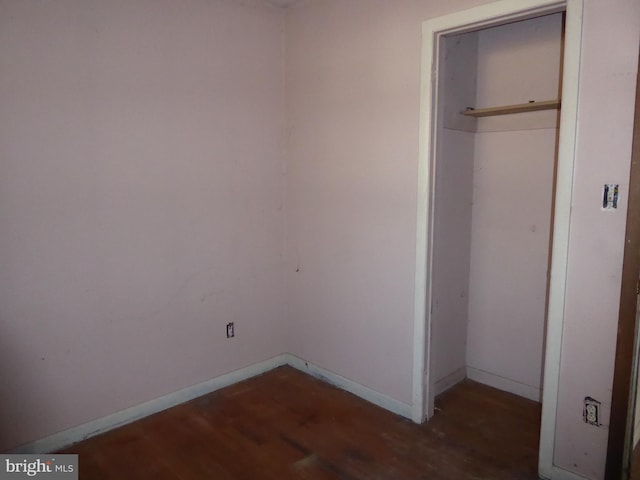 unfurnished bedroom with dark wood-type flooring and a closet