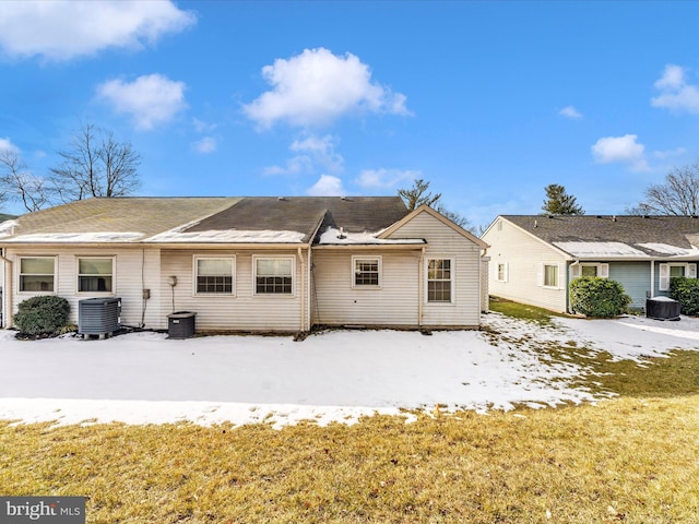 rear view of property with cooling unit and a lawn