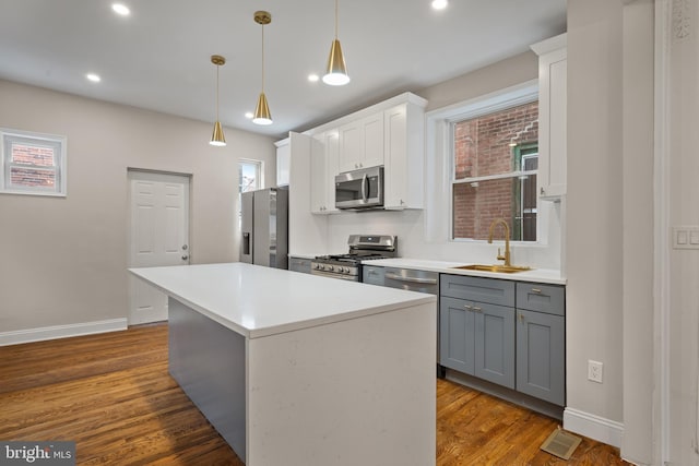 kitchen featuring stainless steel appliances, sink, white cabinets, a center island, and gray cabinets