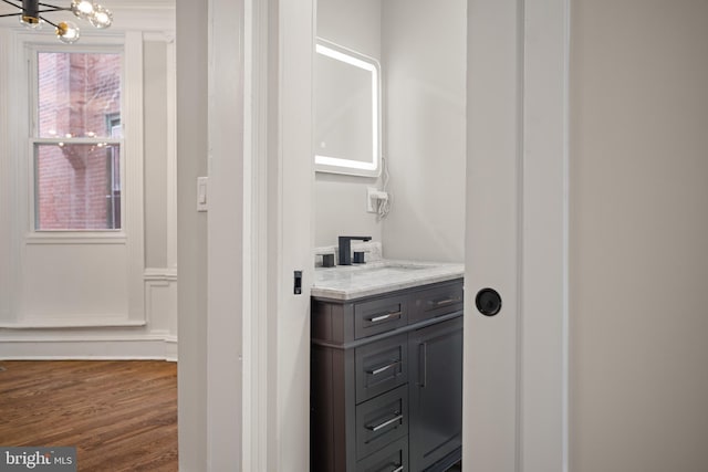 bathroom with wood-type flooring, vanity, and an inviting chandelier