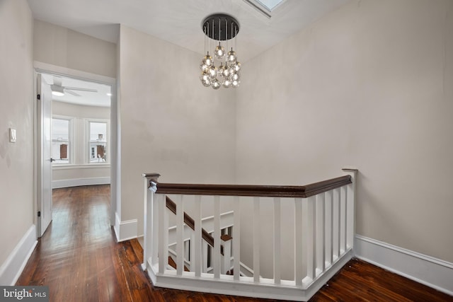 hall featuring dark wood-type flooring and a notable chandelier